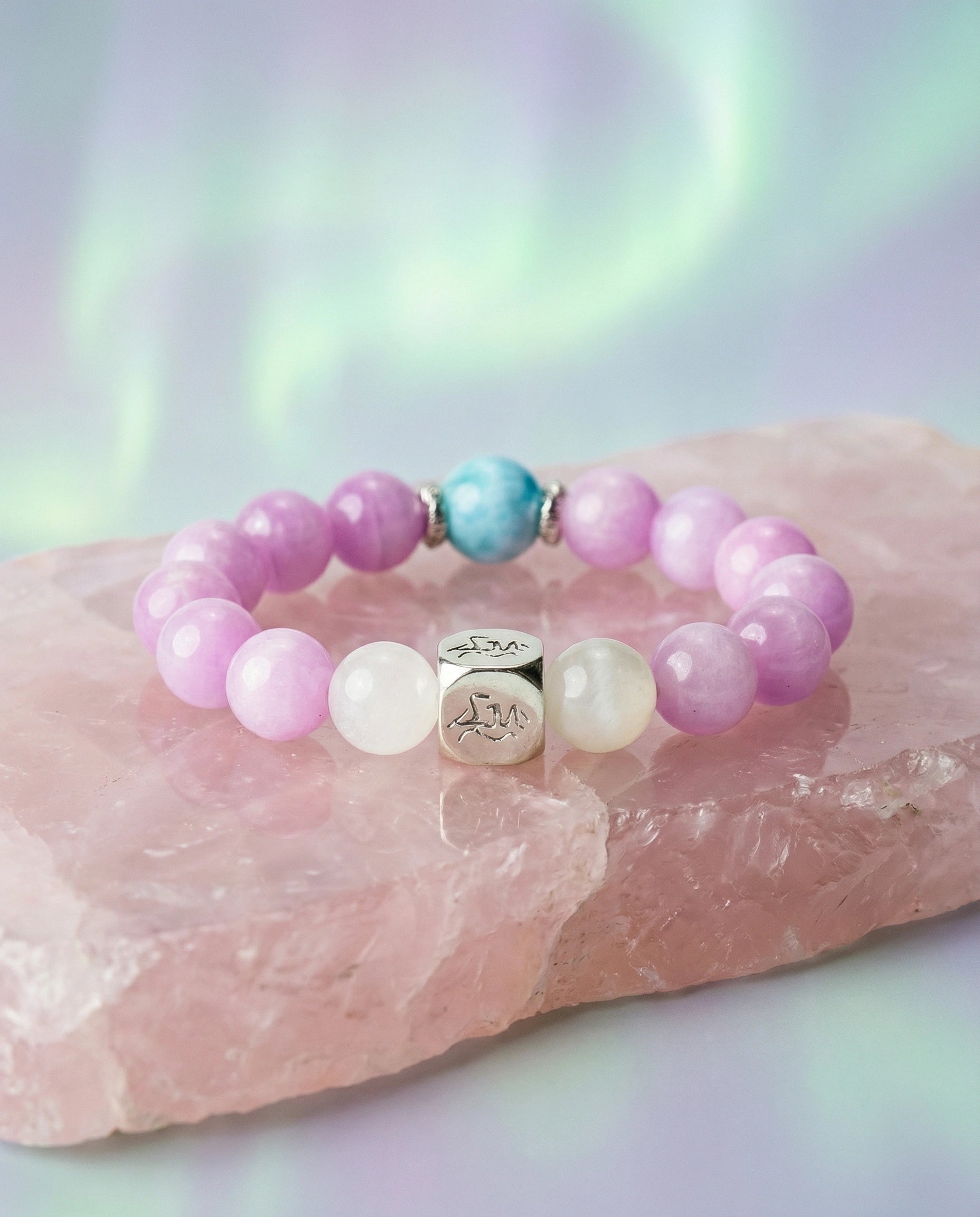 Aurora water crystal bracelet — kunzite larimar and snow quartz — on raw rose quartz with northern lights backdrop — Leymen Jewels