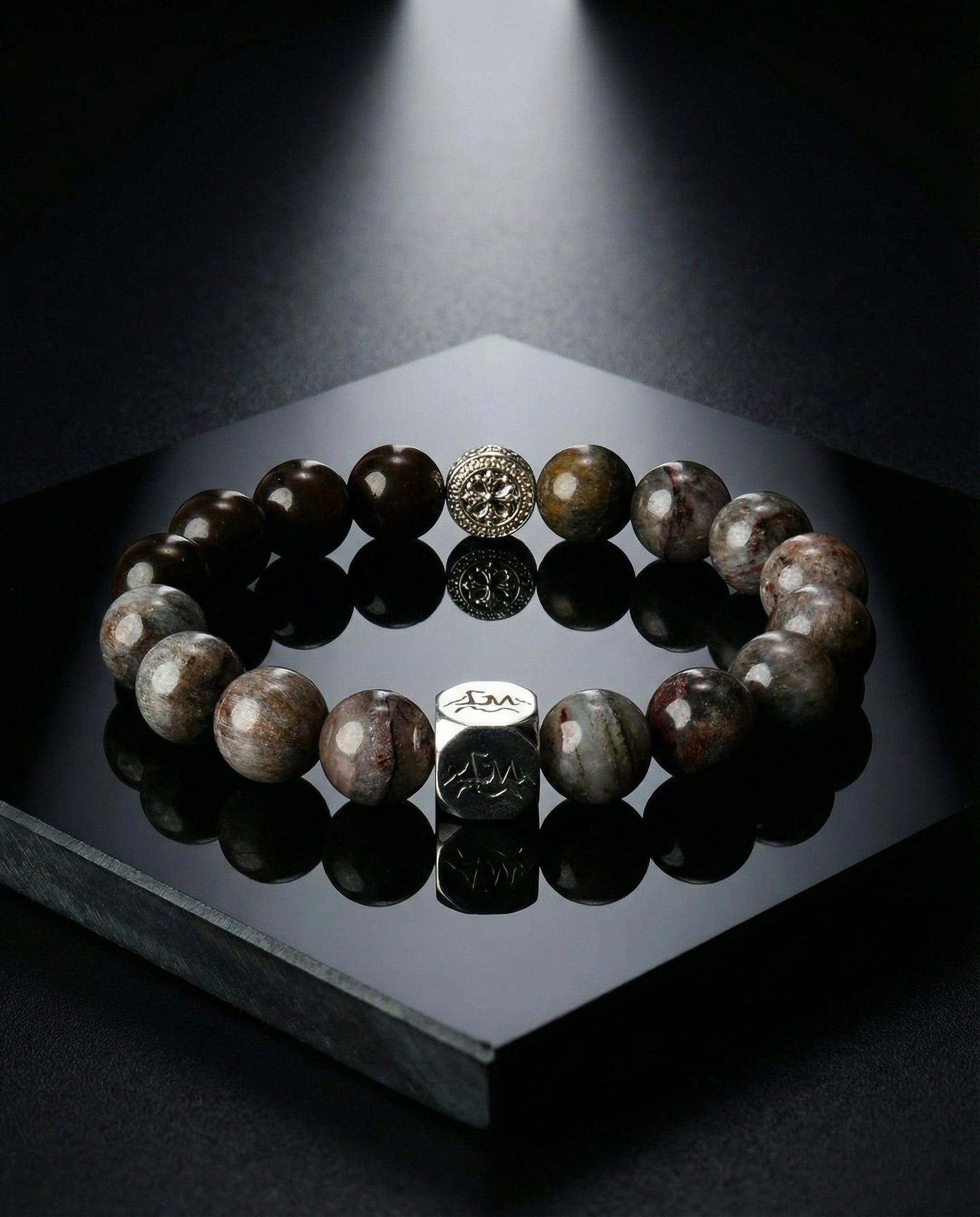 Axis metal crystal bracelet — black auralite-23 and cintamani — on black reflective stone surface with dramatic spotlight — Leymen Jewels