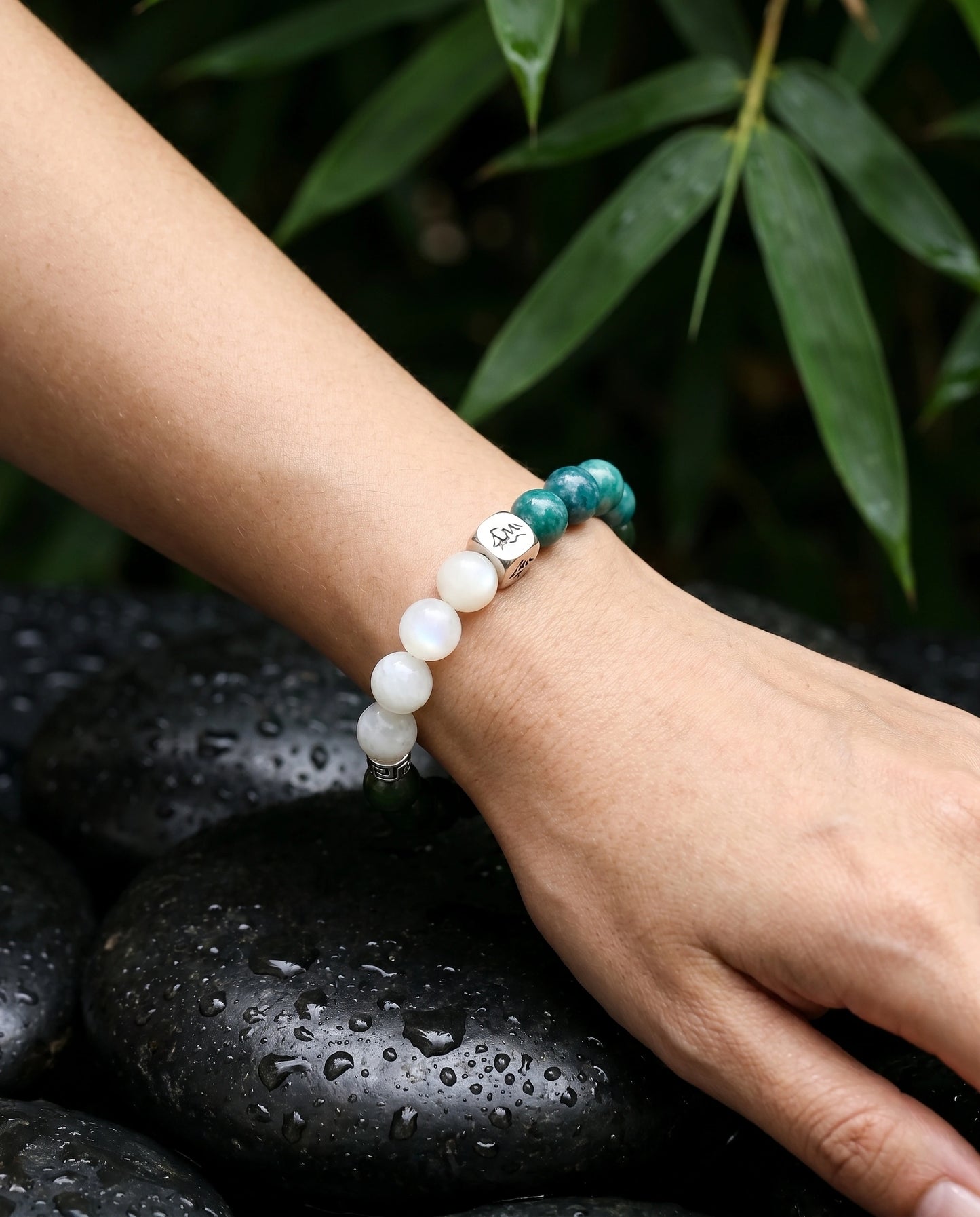 Canopy wood crystal bracelet — teal kyanite and garnierite — worn on wrist over wet black river stones with bamboo — Leymen Jewels