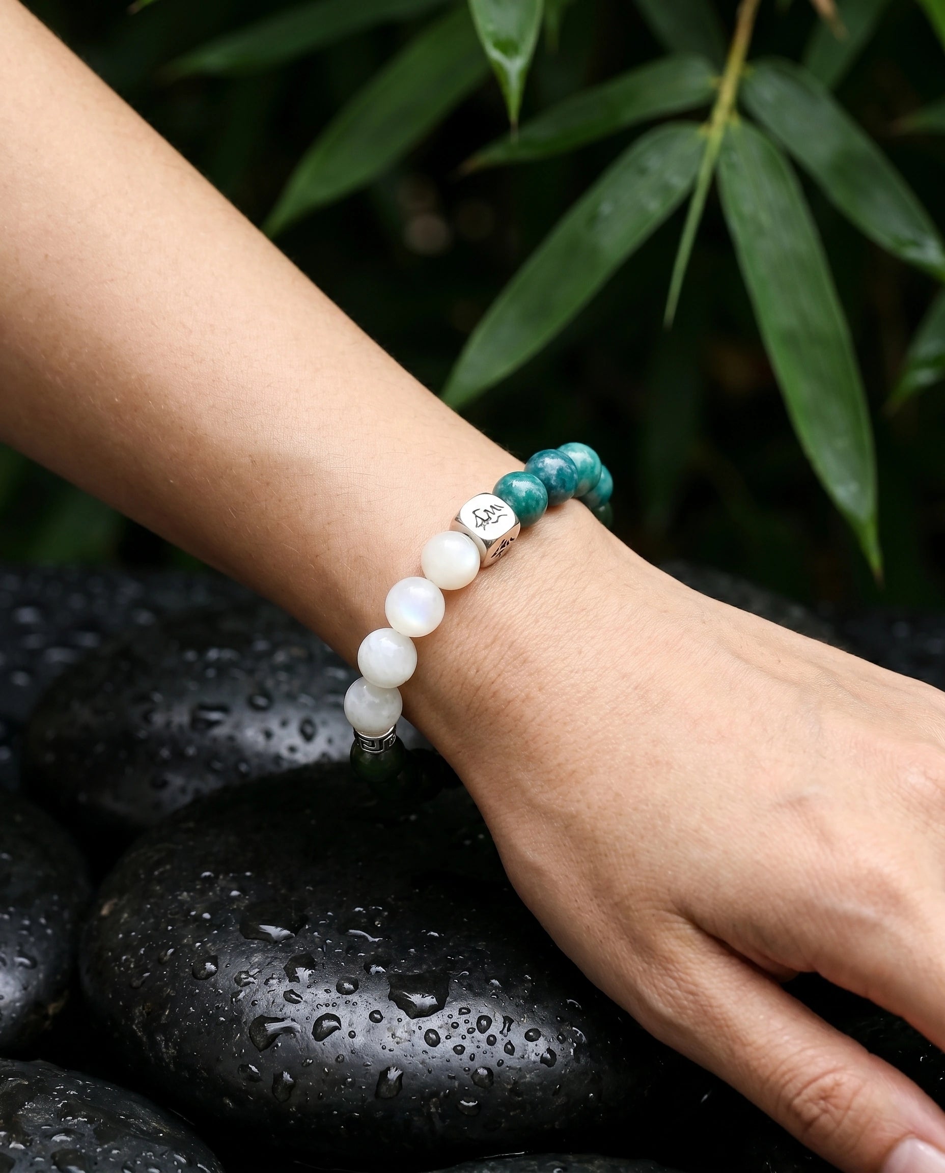 Canopy wood crystal bracelet — teal kyanite and garnierite — worn on wrist over wet black river stones with bamboo — Leymen Jewels