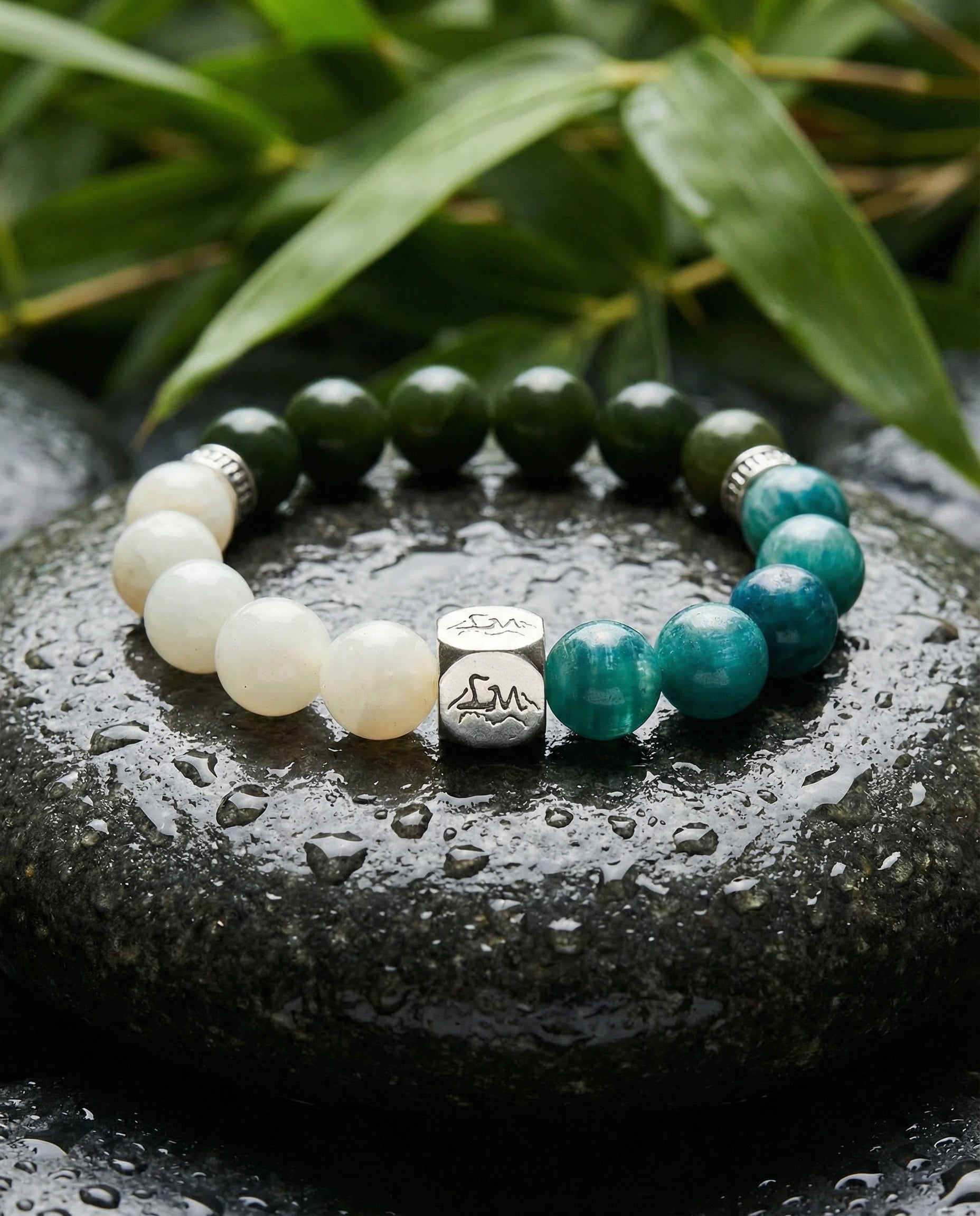 Canopy wood crystal bracelet — teal kyanite and nephrite jade — on wet dark stone with tropical foliage — Leymen Jewels