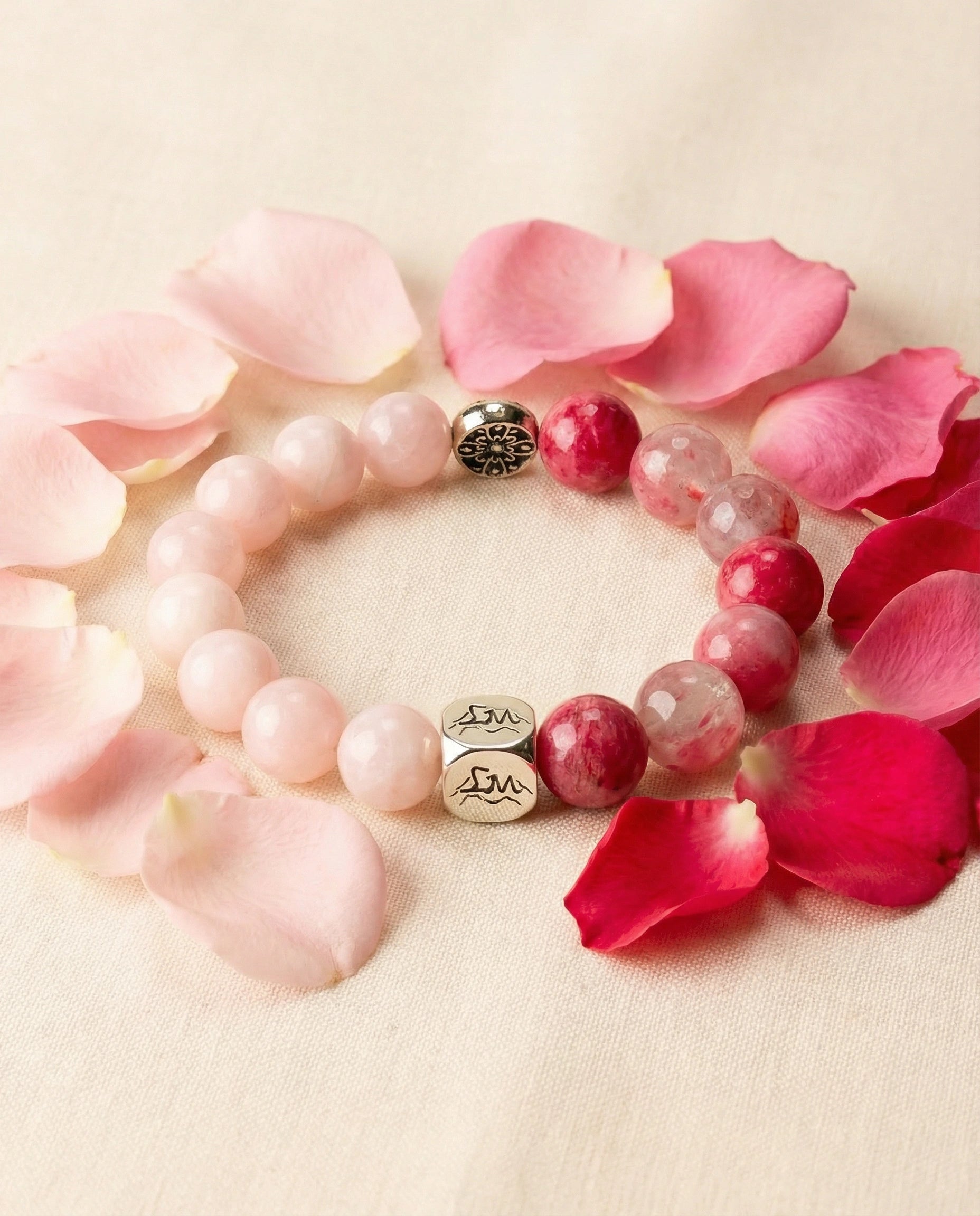 Emberheart fire crystal bracelet — rhodonite and rose quartz — among rose petals on linen — Leymen Jewels