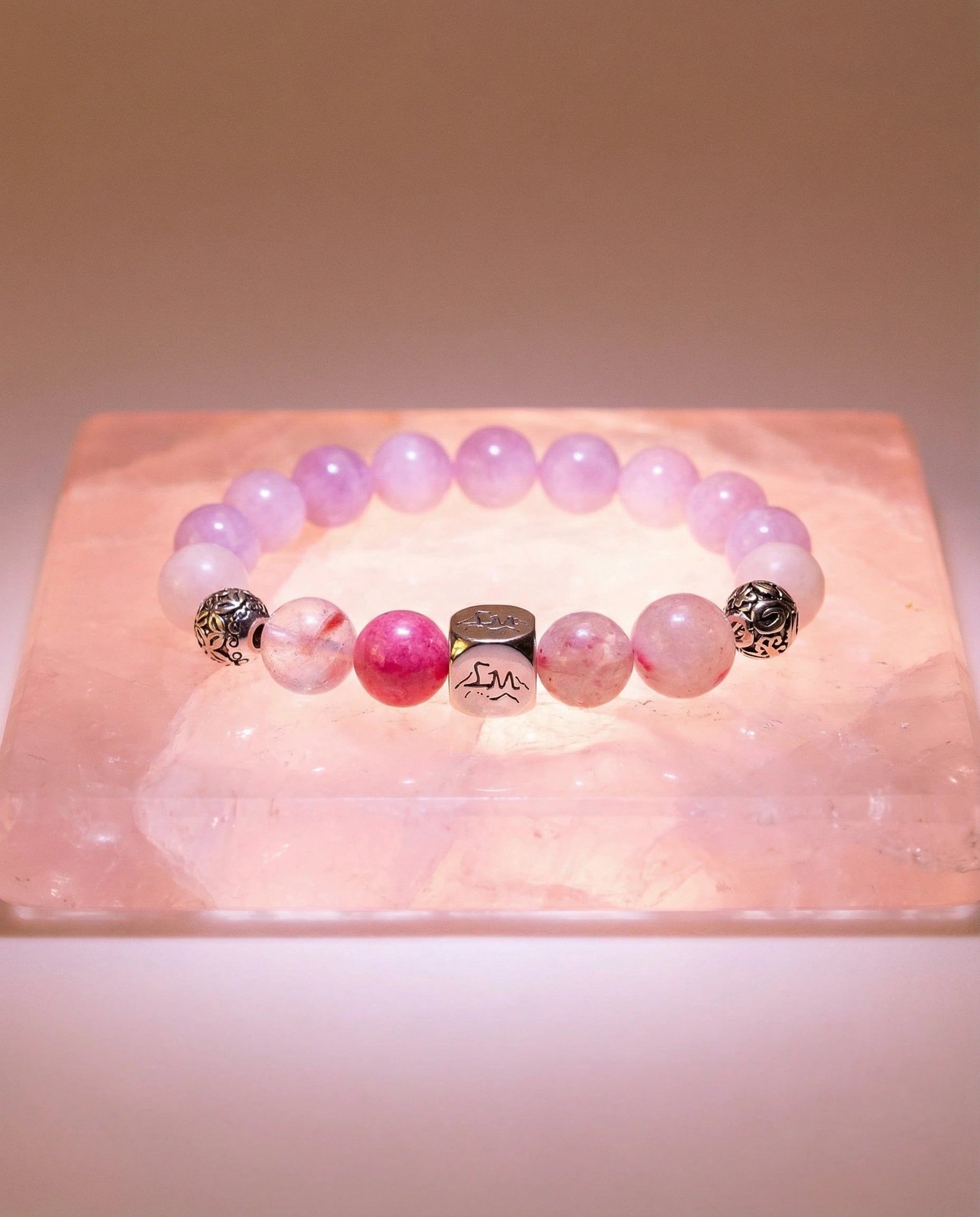 Evania fire crystal bracelet — kunzite, rhodonite, rose quartz — on raw rose quartz slab — Leymen Jewels