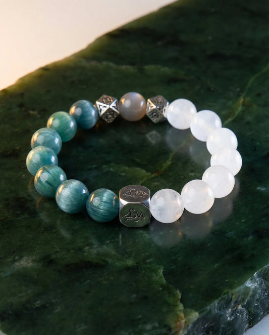 Lumen wood crystal bracelet — teal kyanite and snow quartz — on polished nephrite jade surface with warm light — Leymen Jewels