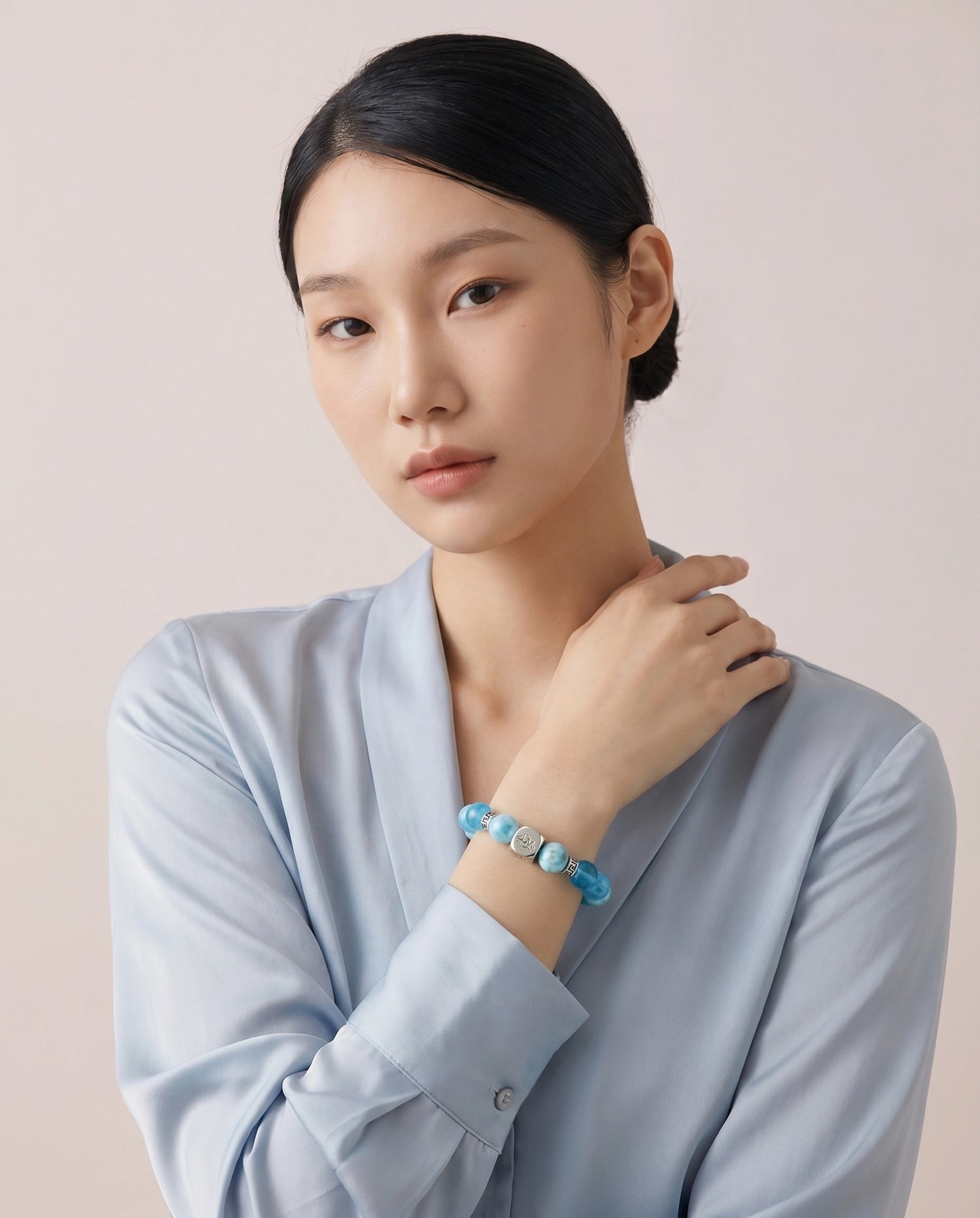 Mariner water crystal bracelet — larimar and dark aquamarine — worn by model against blush studio background — Leymen Jewels