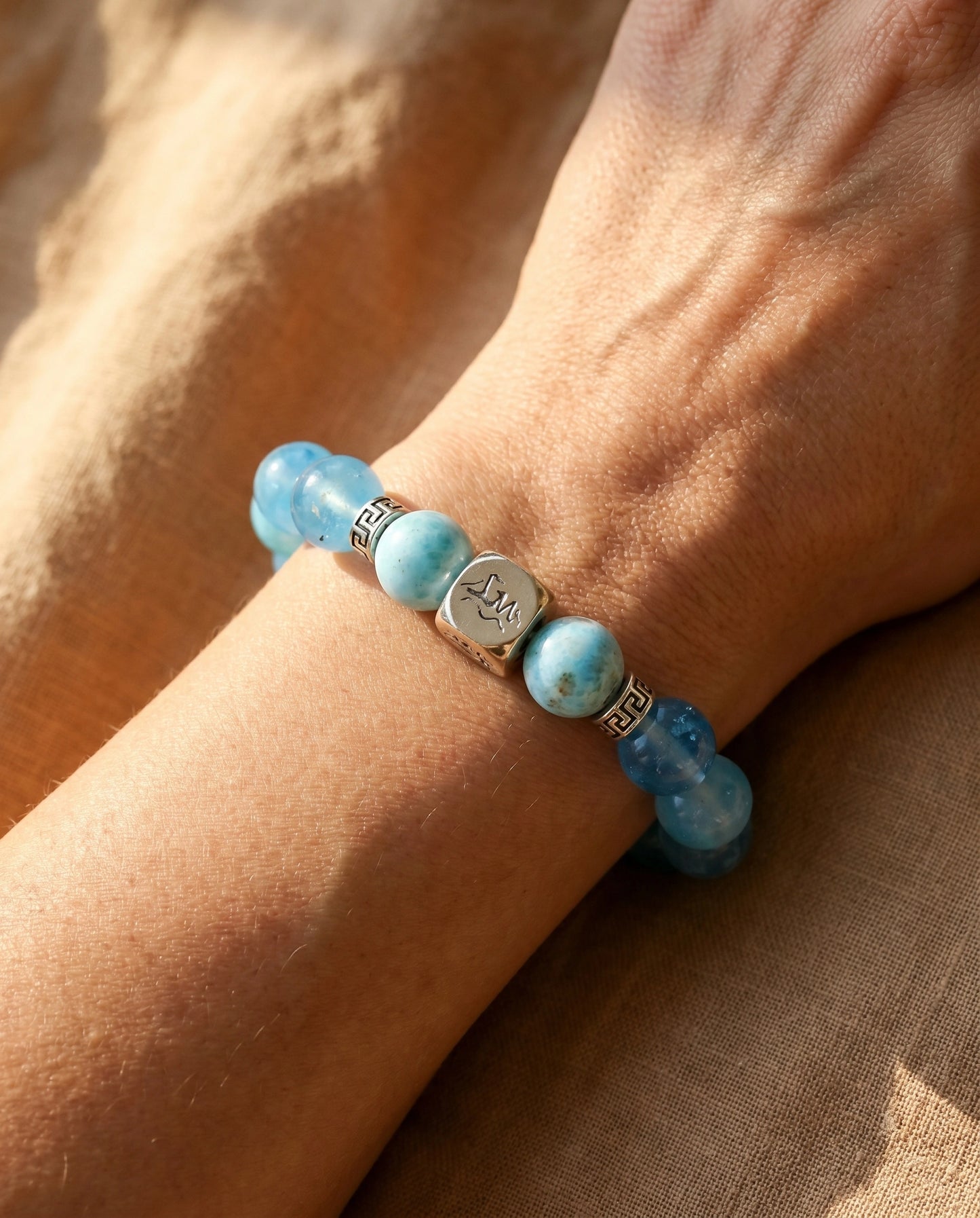 Mariner water crystal bracelet — larimar and dark aquamarine — worn on wrist against warm terracotta linen — Leymen Jewels