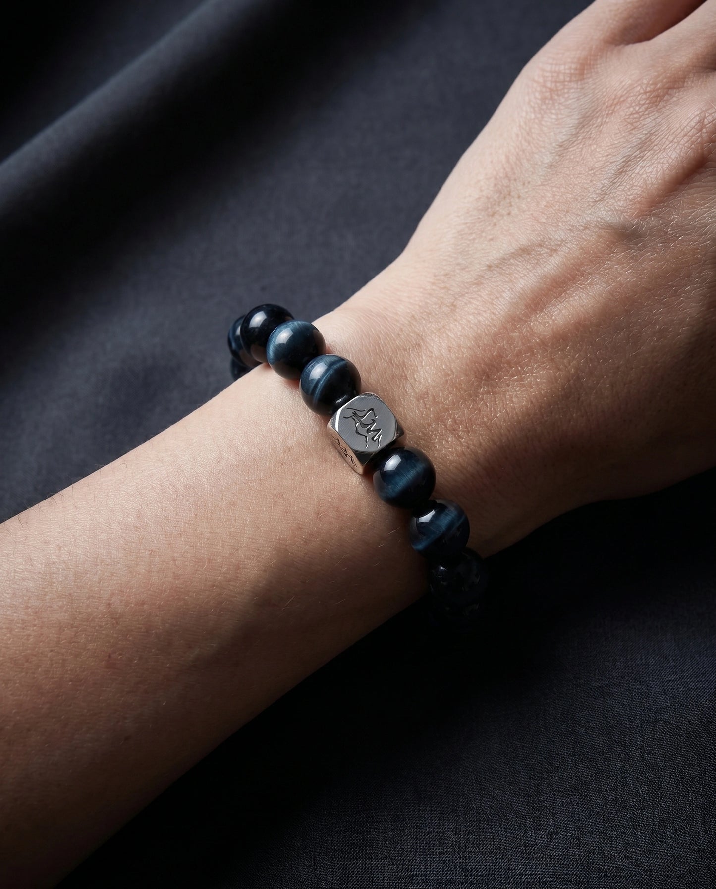 Oracle water crystal bracelet — lapis lazuli and blue tiger's eye — worn on wrist against dark charcoal fabric — Leymen Jewels