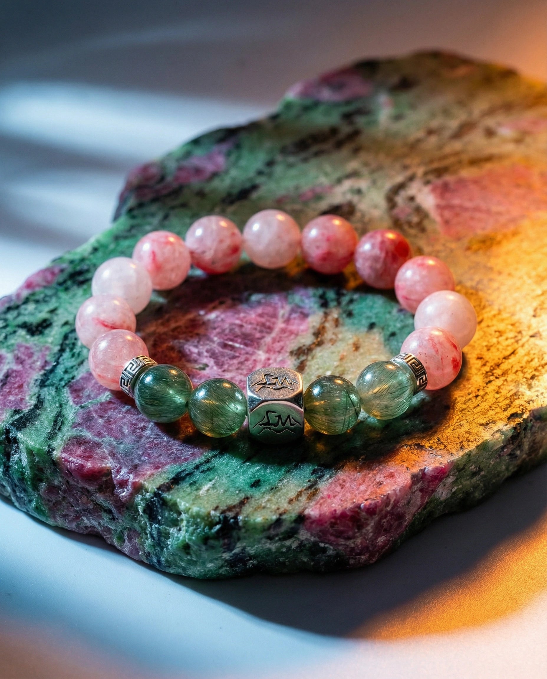 Phoenix fire crystal bracelet — rhodonite and green rutilated quartz — on ruby zoisite mineral slab — Leymen Jewels