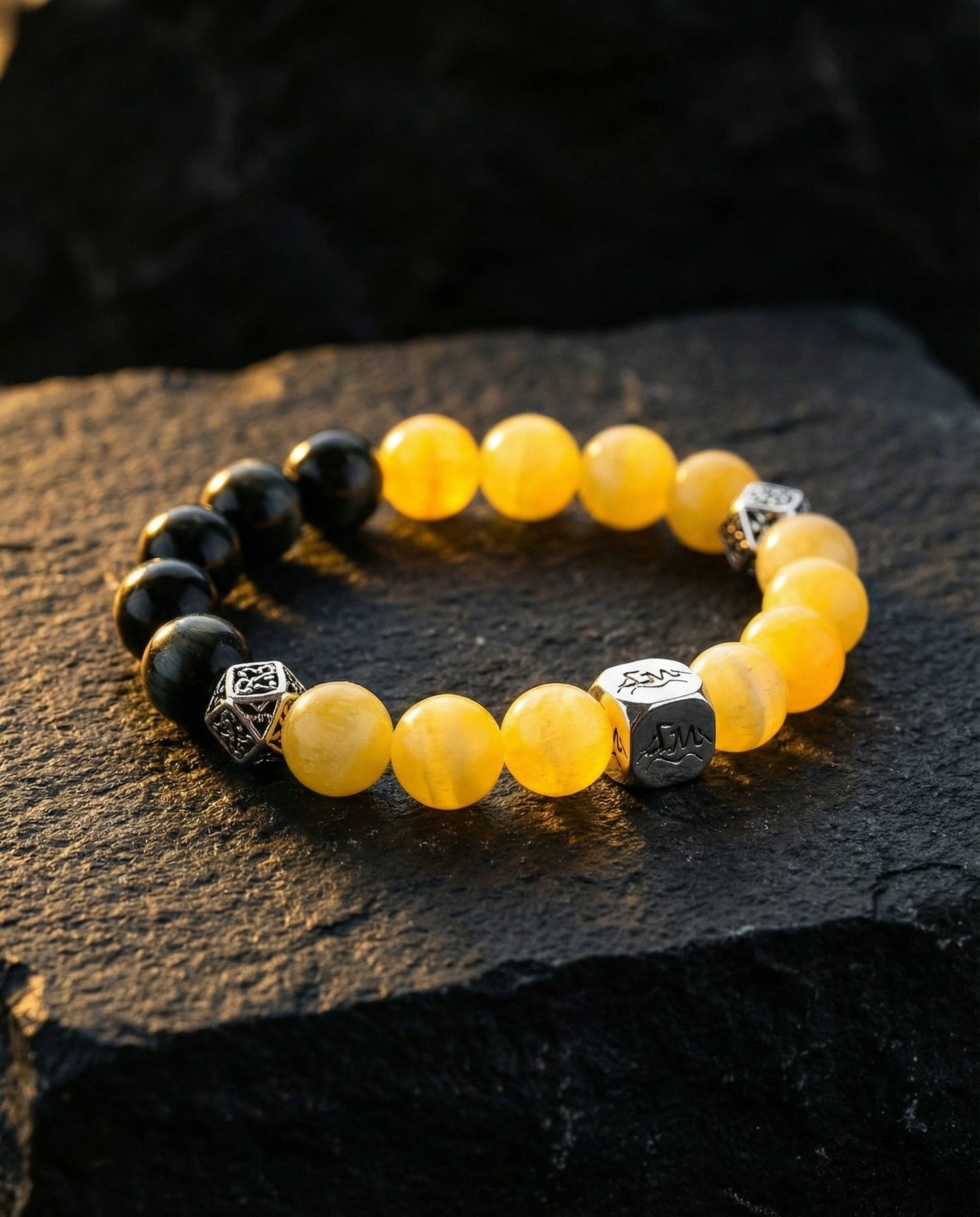 Pillar earth crystal bracelet — yellow calcite and black tiger's eye — on dark slate rock — Leymen Jewels