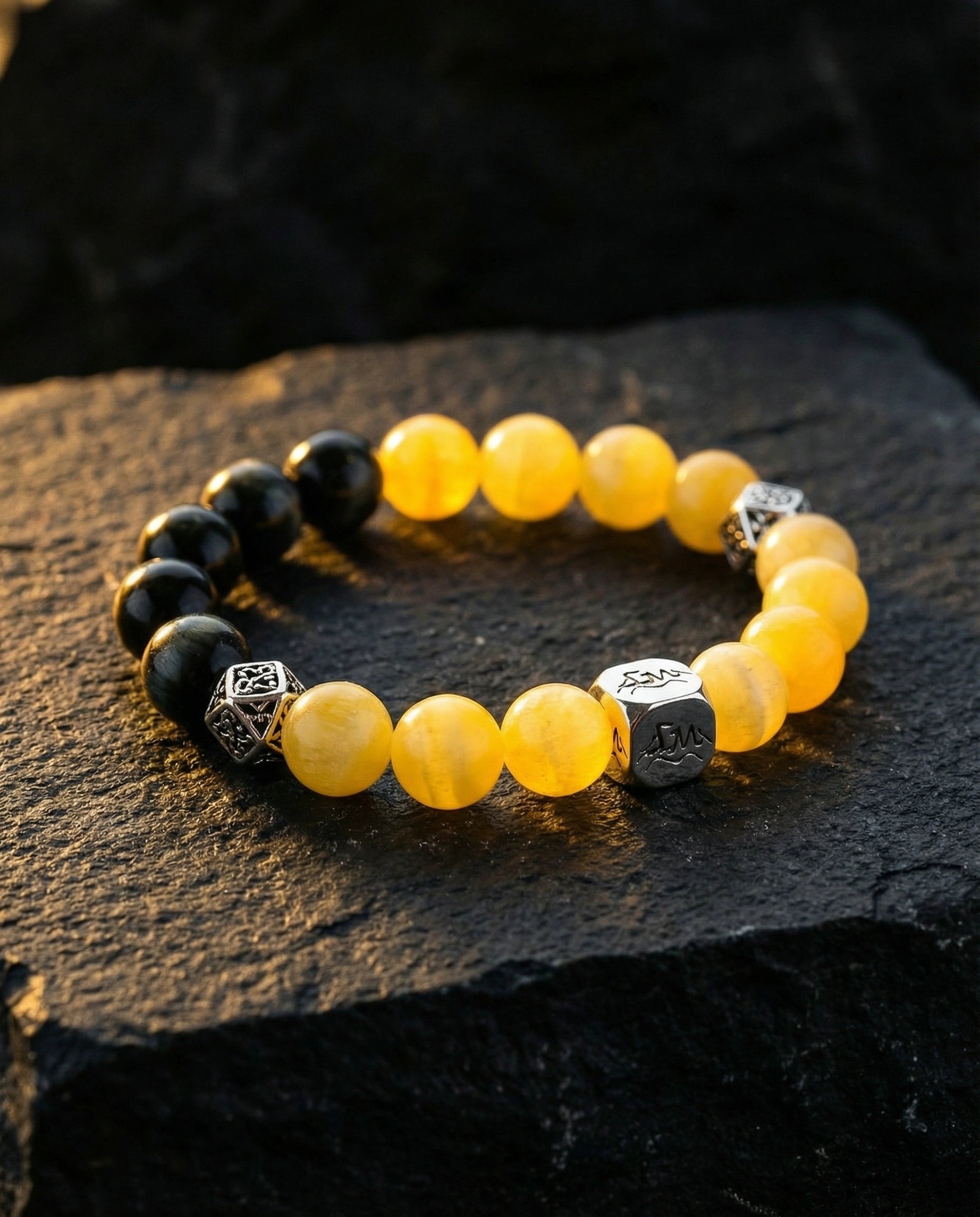 Pillar earth crystal bracelet — yellow calcite and black tiger's eye — on dark slate rock — Leymen Jewels