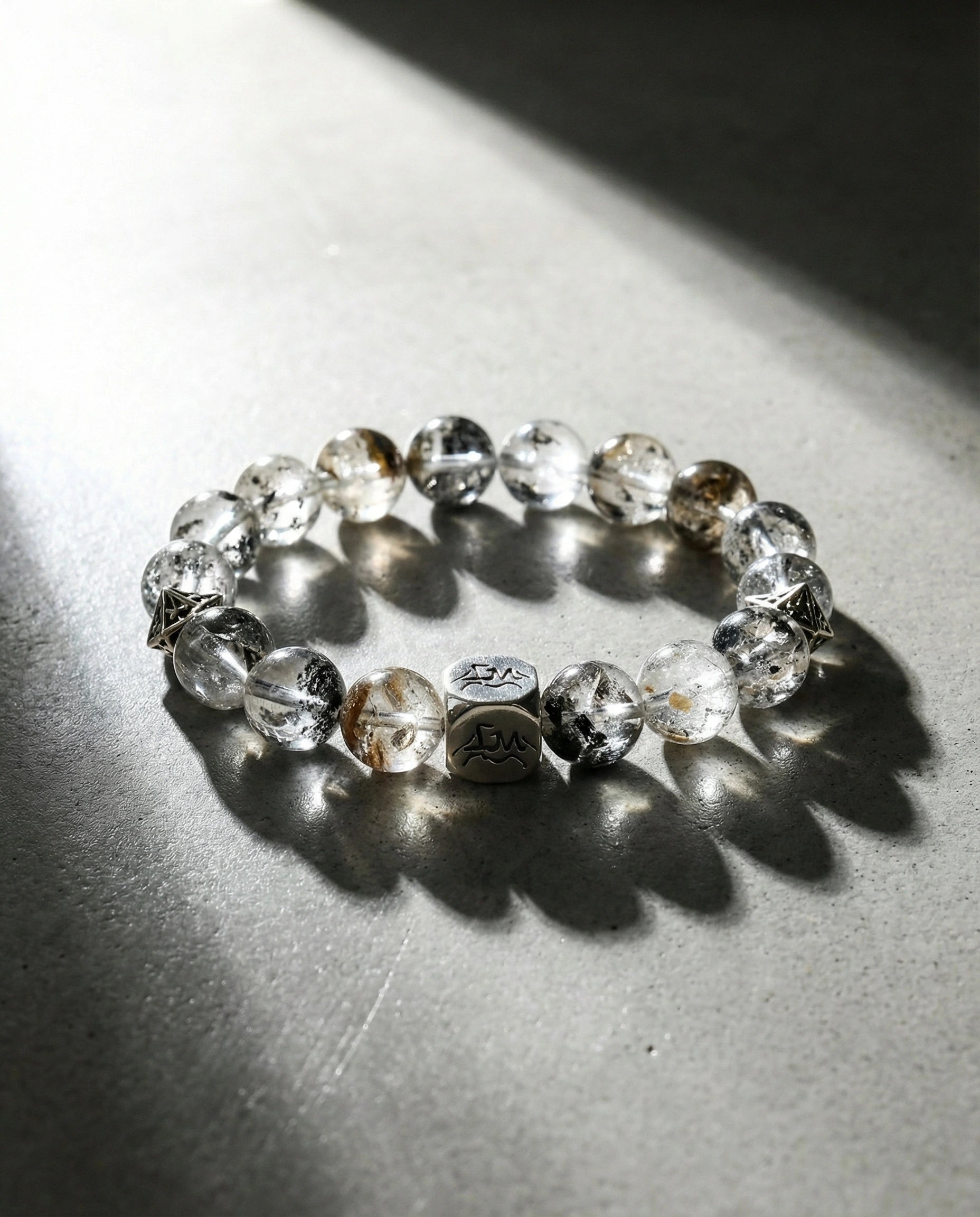 Prism metal crystal bracelet — herkimer diamond with silver geometric accent beads — on concrete surface with dramatic light and shadow — Leymen Jewels