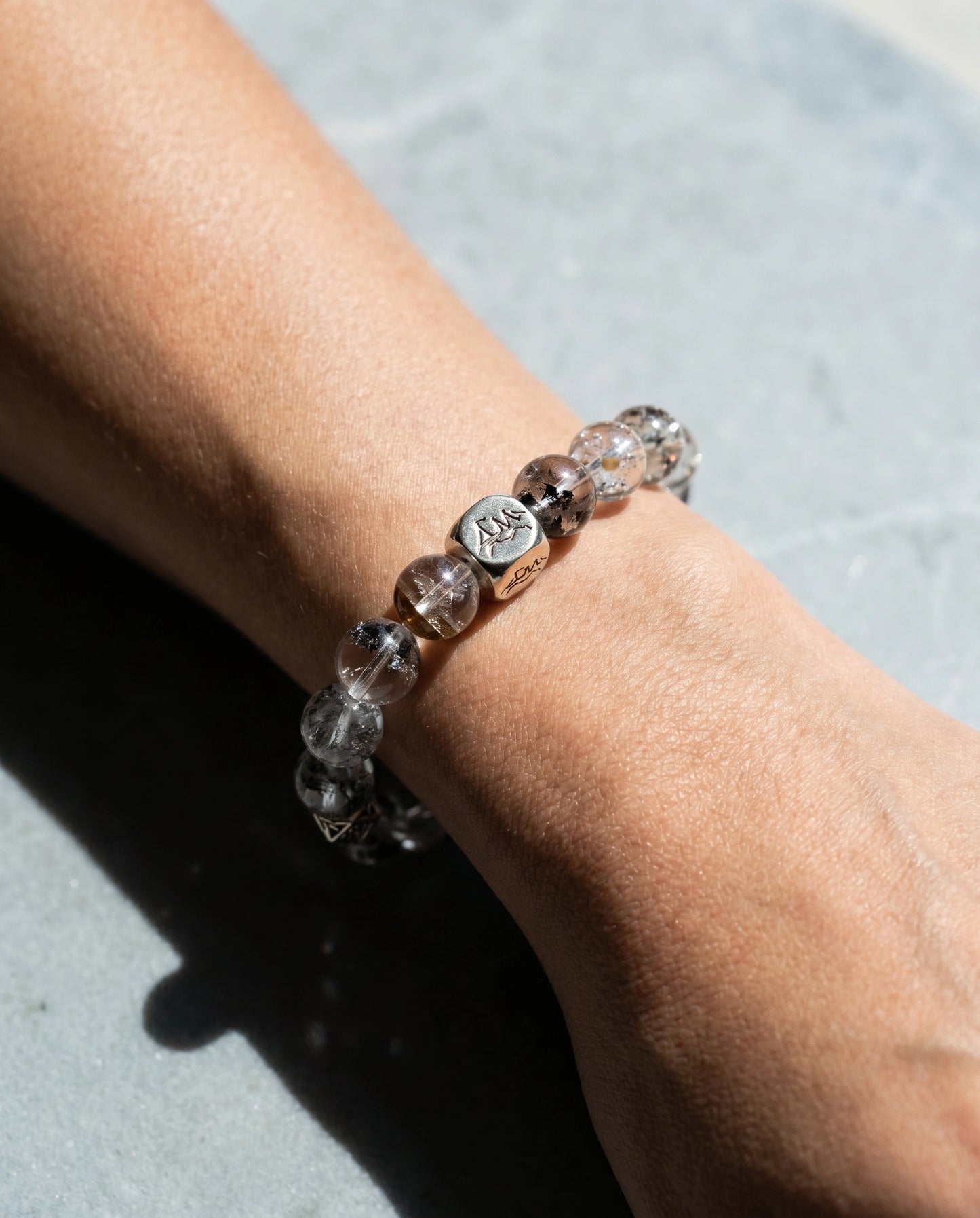 Prism metal crystal bracelet — herkimer diamond — worn on wrist in bright sunlight on grey stone surface — Leymen Jewels