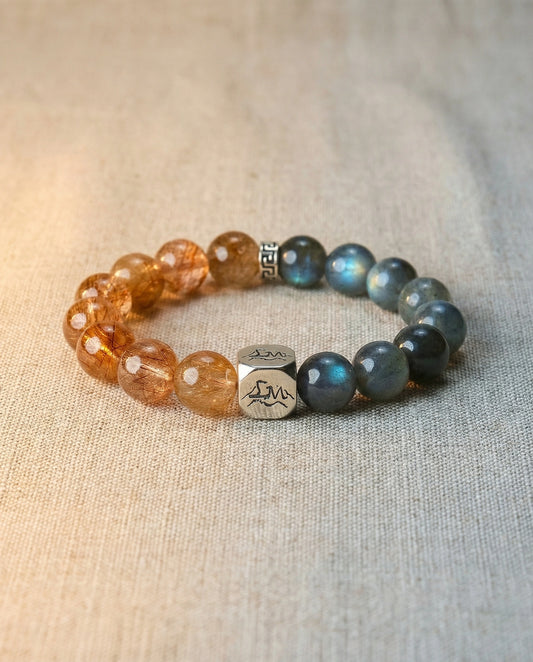 Solace metal crystal bracelet — copper rutilated quartz and grey moonstone — on natural linen surface with warm light — Leymen Jewels