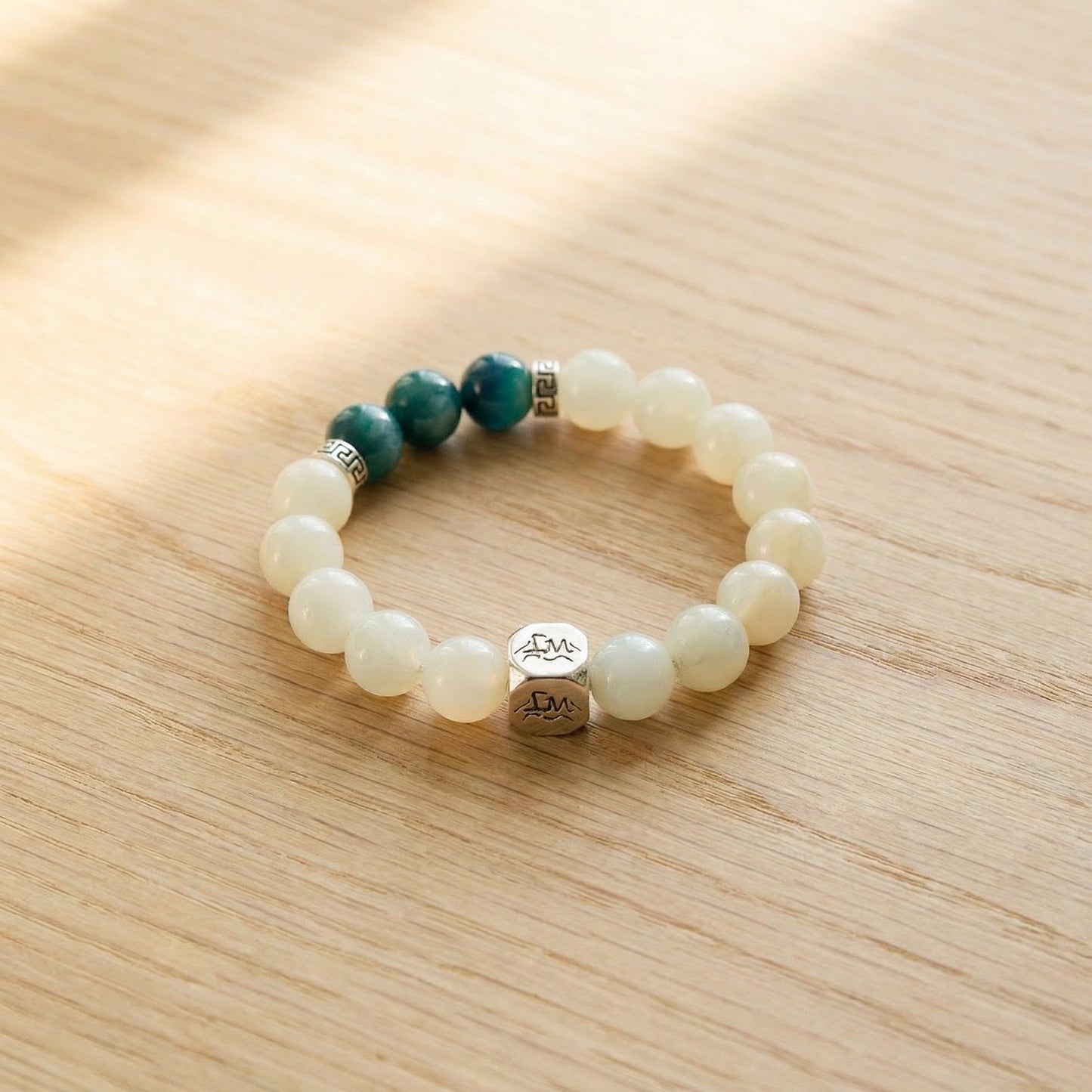 Sylva wood crystal bracelet — teal kyanite and garnierite — on natural pale wood surface with warm light — Leymen Jewels