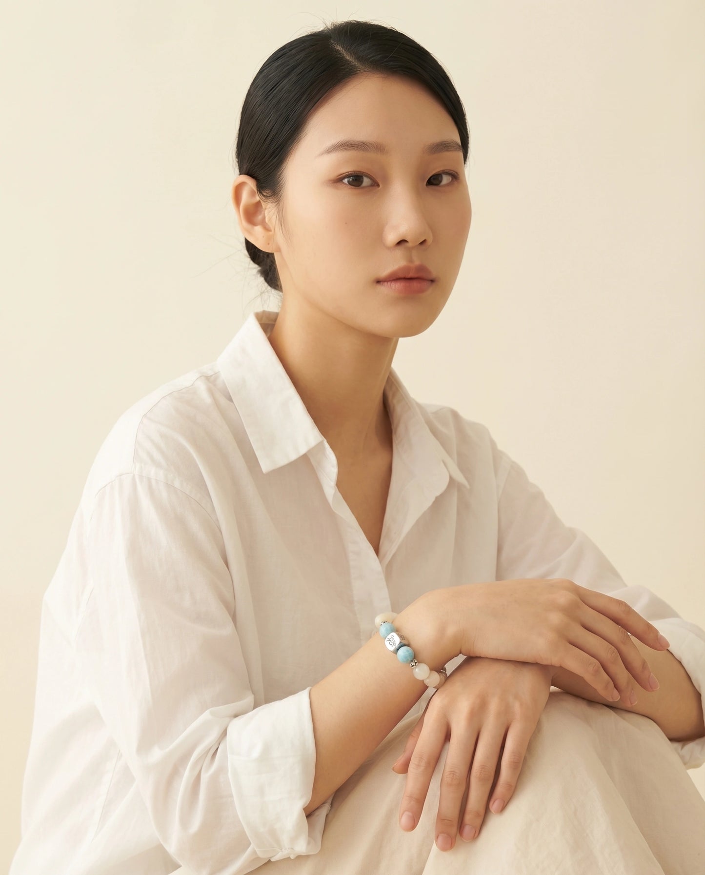 Tideborne water crystal bracelet — larimar and garnierite — worn by model in white shirt against cream background — Leymen Jewels