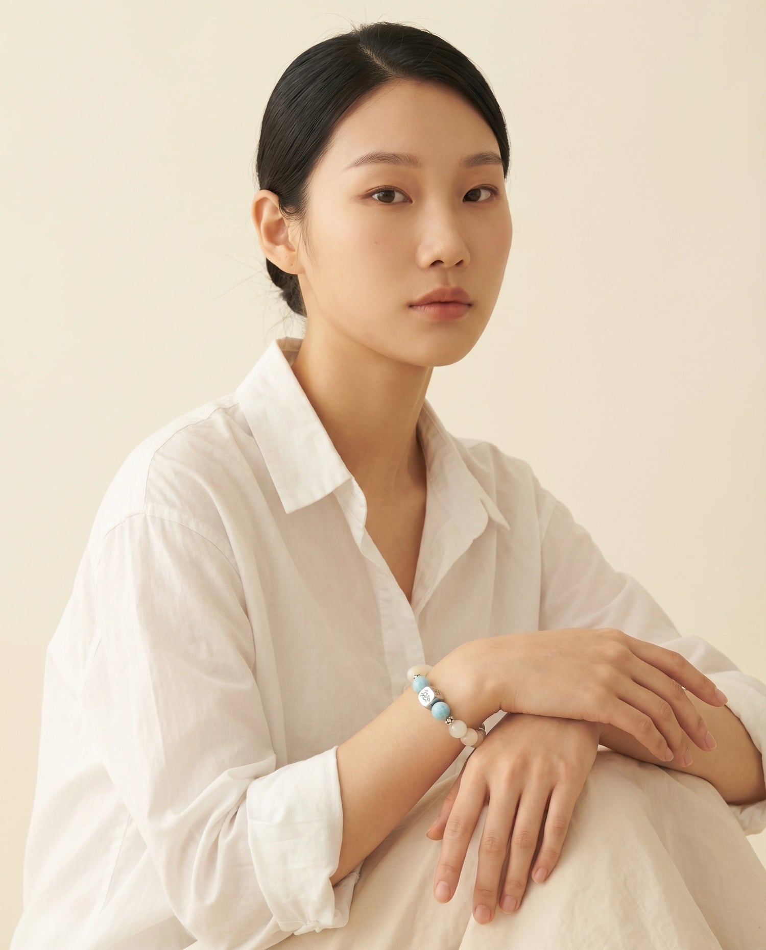 Tideborne water crystal bracelet — larimar and garnierite — worn by model in white shirt against cream background — Leymen Jewels
