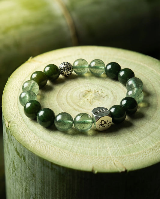 Verdant wood crystal bracelet — nephrite jade and green rutilated quartz — on fresh-cut bamboo with lush green foliage — Leymen Jewels