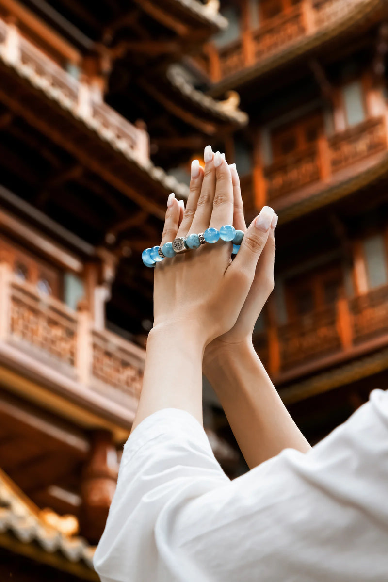 Leymen Jewels water element aquamarine crystal bracelet worn in prayer at a traditional Chinese wooden temple — ancient wisdom for modern balance